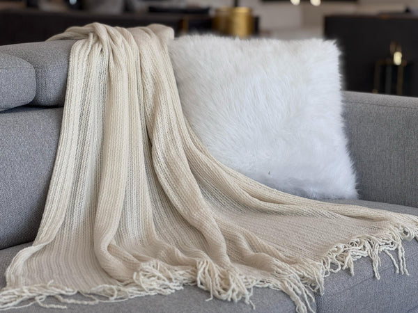 Soft Levi Throw Rug Blanket in cream draped over a sofa, creating a warm and inviting look.