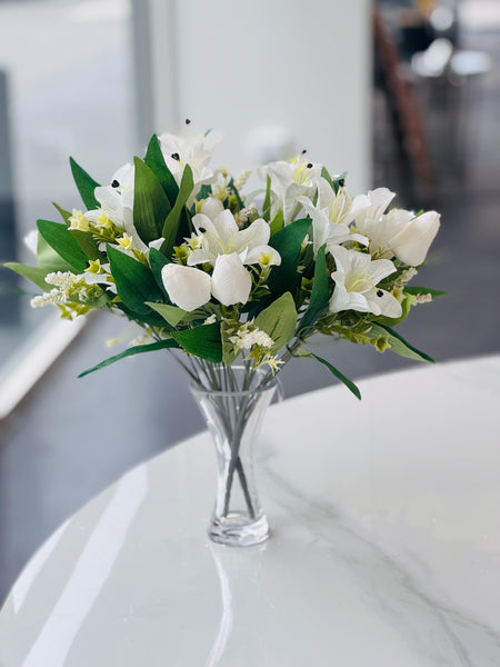 White lily and tulip bunch arranged in a clear vase, adding elegance to any table.