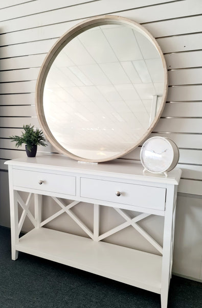 Large natural wood round mirror styled on white console table with décor accents