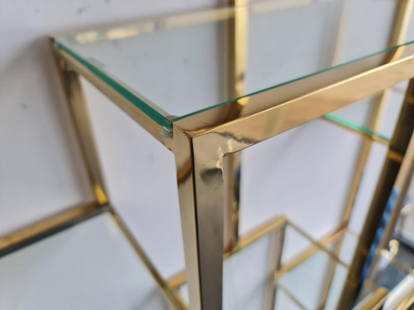 Close-up detail of the Nelson Bookcase in polished gold finish, showcasing the beveled glass shelf and sleek stainless steel frame with high-quality craftsmanship.