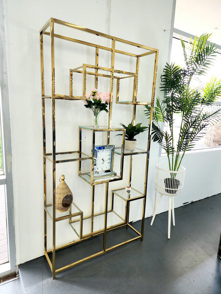 Nelson Bookcase in polished gold finish styled with decorative vases, photo frames, and greenery – side view highlighting its geometric structure and modern design.