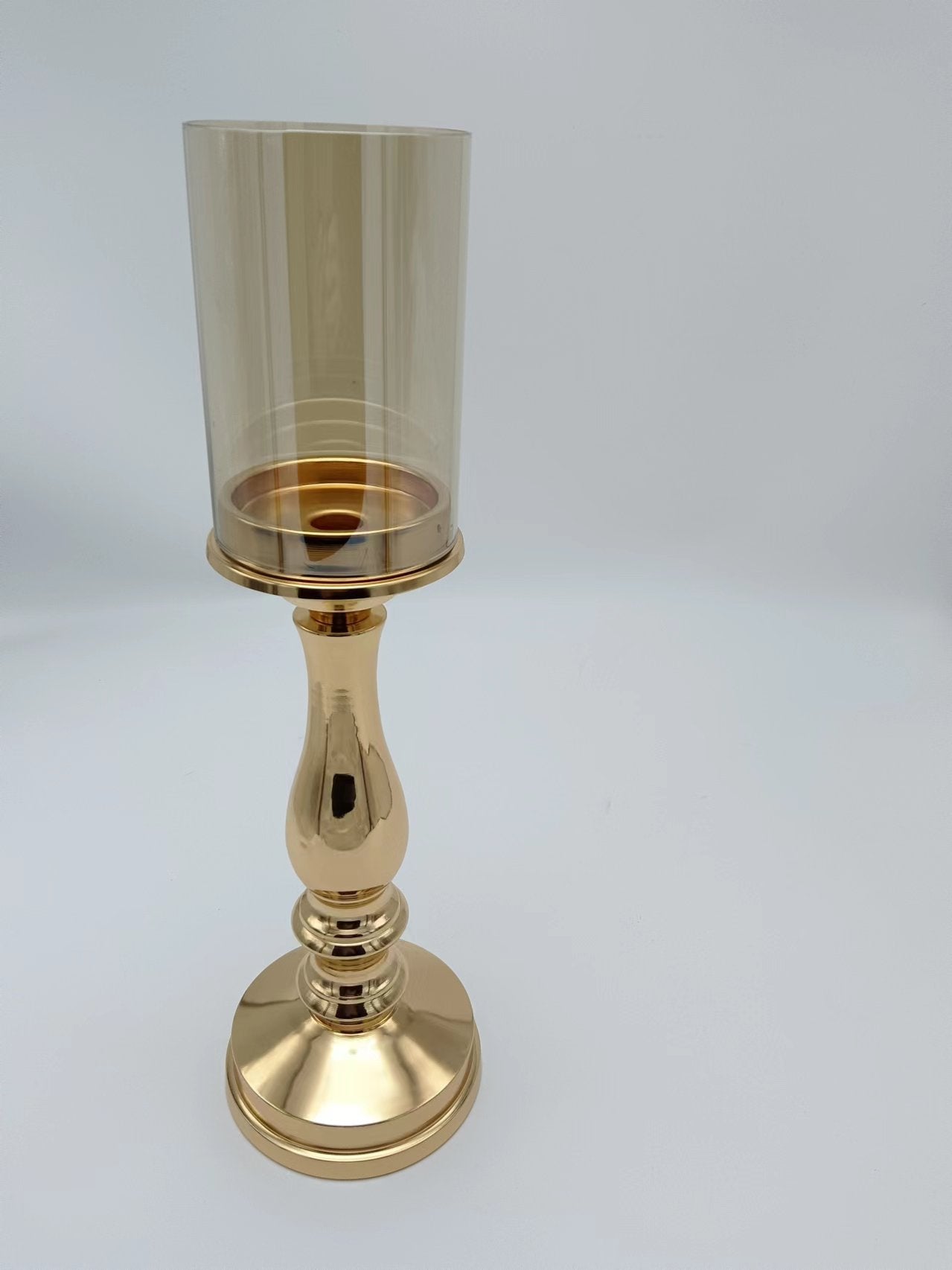 Petite gold pillar candle holder with elegant detailing and a warm-toned glass shade, suitable for refined table settings