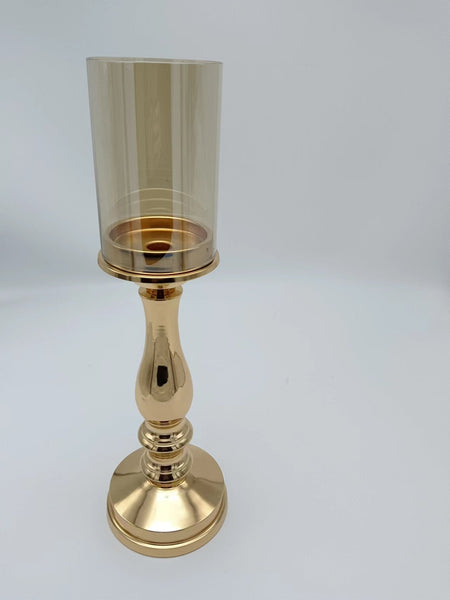 Petite gold pillar candle holder with elegant detailing and a warm-toned glass shade, suitable for refined table settings