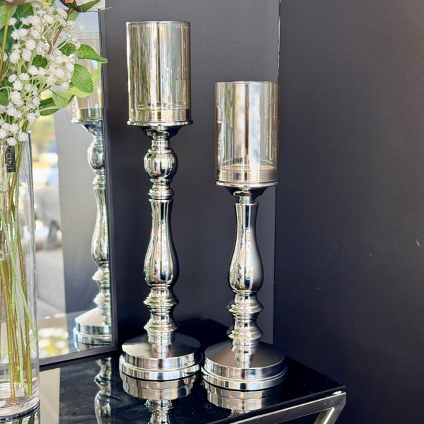 Elegant silver pillar candle holders displayed in a modern setting with mirror and reflective accents, ideal for upscale home décor arrangements
