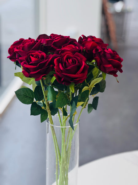 Close-up of red artificial roses in a clear vase showcasing rich color and detail.
