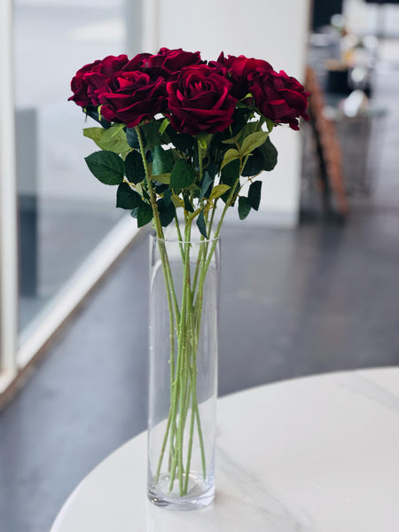  Elegant arrangement of red artificial roses in a tall clear glass vase.