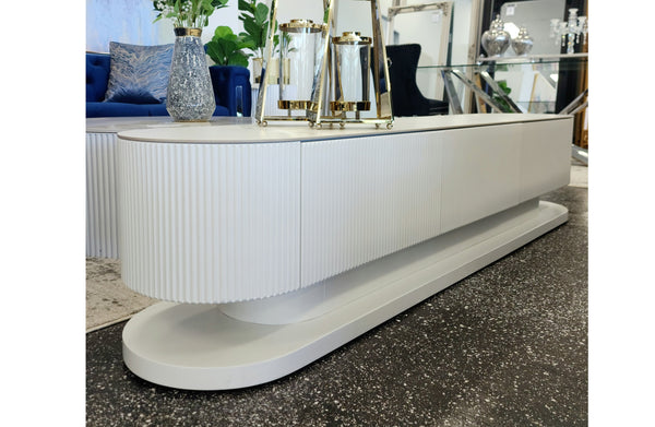 White ripple TV unit displayed in showroom with gold decorative accessories