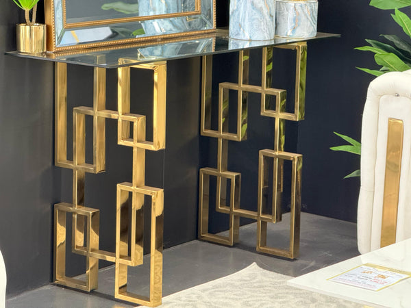 Royale console table with gold frame and clear glass top styled with mirror and décor.
