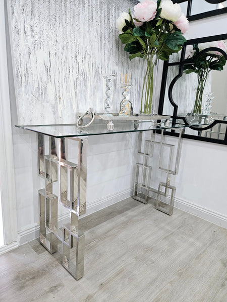 Royale console table with silver frame and clear glass top styled with flowers and décor.