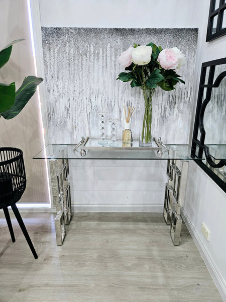 Royale console table with silver frame and glass top styled in a modern entryway setting.