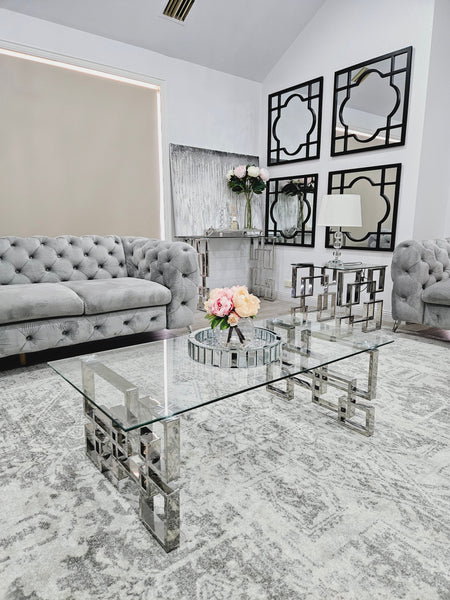 Royale silver coffee table with clear glass top styled in a modern grey living room.