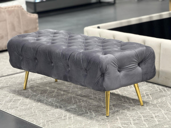 Dark Grey Shirley Ottoman with gold legs and tufted velvet seating, chic room accent.