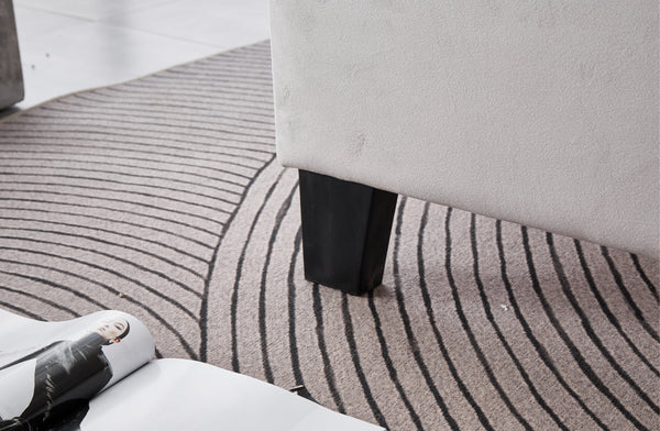 Close-up of sturdy black wooden leg on Winston Velvet Tufted Bed in light grey.